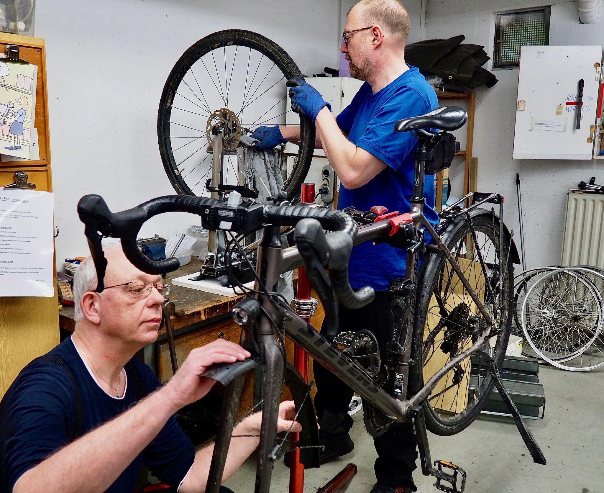 Selbsthilfewerkstatt Frankfurt | © Eckehard Wolf Bild von einer Selbsthilfewerkstatt mit einem Fahrrad und 2 Männern, die dieses reparieren.
