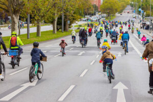 Viele Radfahrende, Erwachsene und Kinder, fahren auf der Straße vor dem Wiesbadener Hauptbahnhof. Diese Fahraddemonstration für Kinder heißt "Kidical Mass".