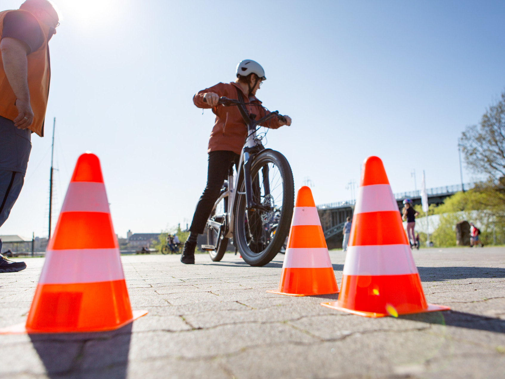 Radfahrerin mit Anleiter - Markierungs-Hütchen im Vordergrund