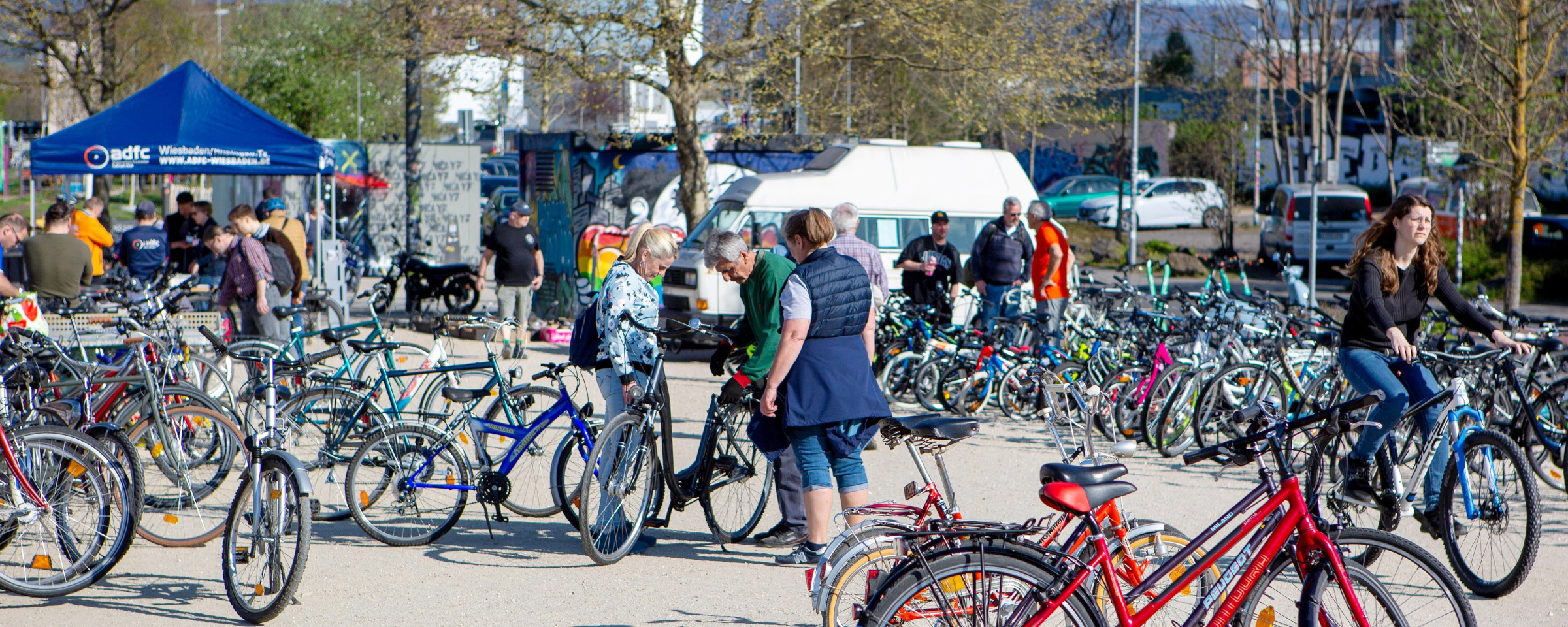 2025_radboerse-am-schlachthof_headerbild3_oliver-kessler_5x2 Viele Fahrräder, die zum Verkauf stehen. Dazwischen Menschen, die die Räder ansehen. Im Hintergrund: Infostand des ADFC | © Ollo Keßler