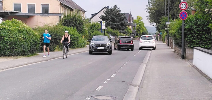 ADFC_FKT Eltville_Schwalbacher Straße Falschparker_Foto_Elke-Tegeler Person auf einem Fahrrad, die neben einem Auto links vor der Bushaltestelle auf den Gehweg abbiegt am Wiesbadener Bahnhof