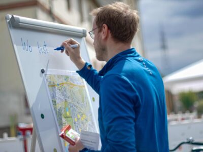 Mann schreibt auf einem Flipchart - mit einer Überblicks-Karte des Stadtteils Biebrich