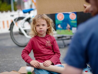 Sitzendes Kind blickt entschlossen in die Kamera