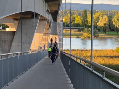 Menschen radeln über den neuen abgehängten Radsteg an der Schiersteiner Brücke über den Rhein