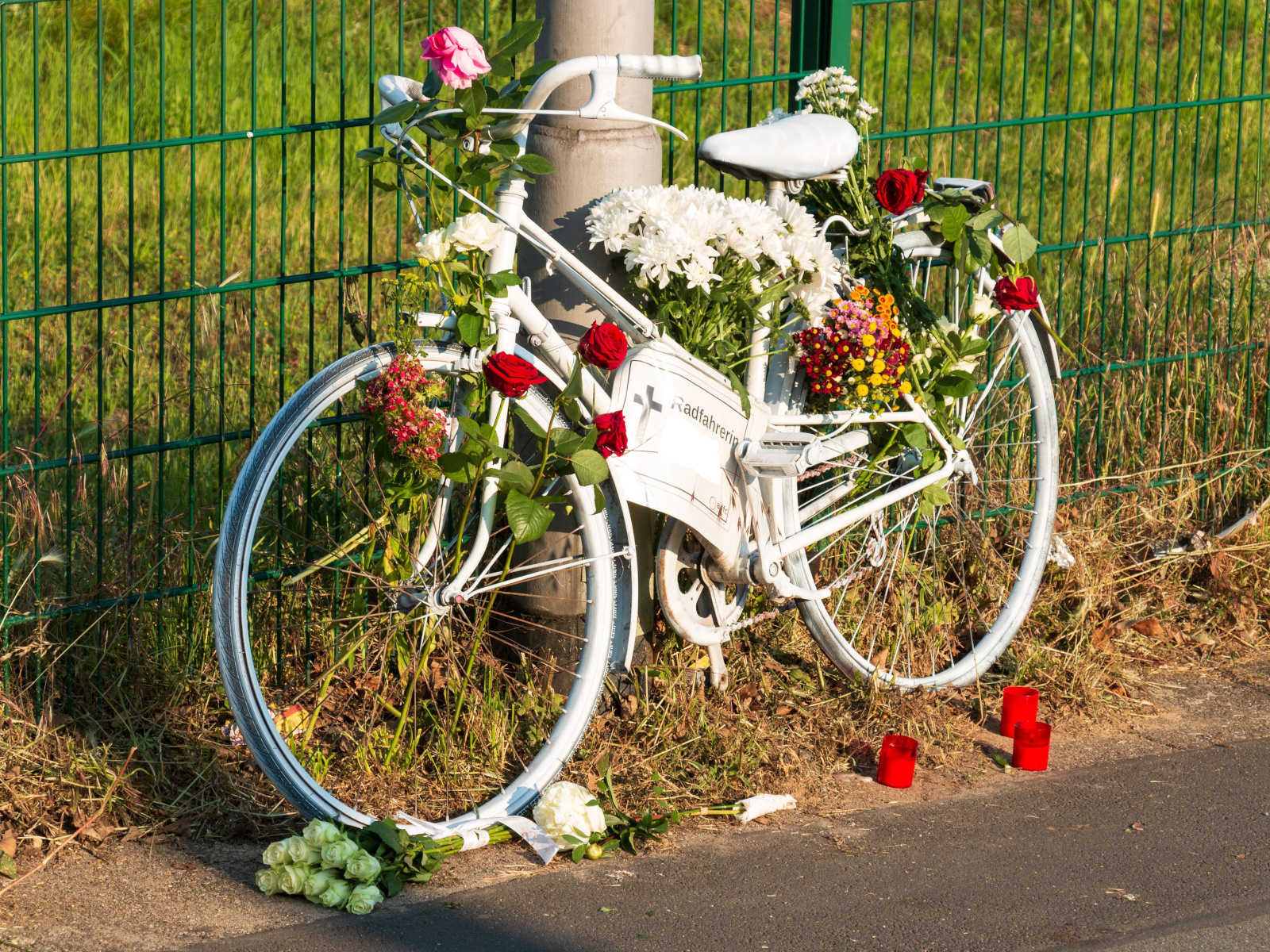 Weißes "Geisterrad", geschmückt mit Blumen. Zum Gedenken an eine bei einem Unfall verstorbene Radfahrerin. Und als Mahnmal.